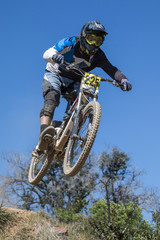 Fototapeta na wymiar Downhill competition, Biker jumps fast in the countryside.
