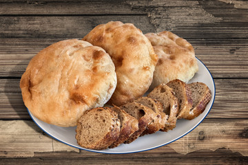 Plate with Pita Bread loafs and Baguette slices, on old Wood.