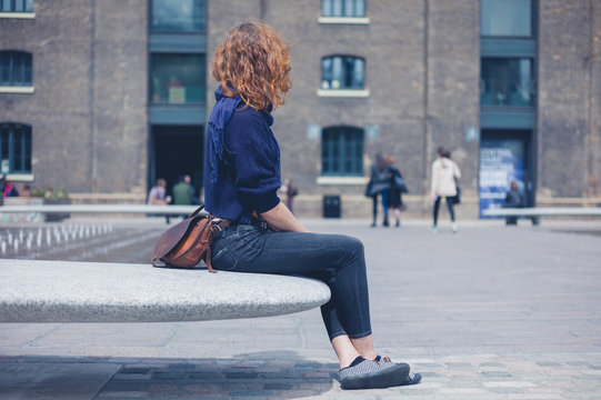 Young woman sitting on granite bench