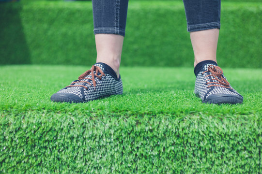 Feet of young woman standing on astro turf