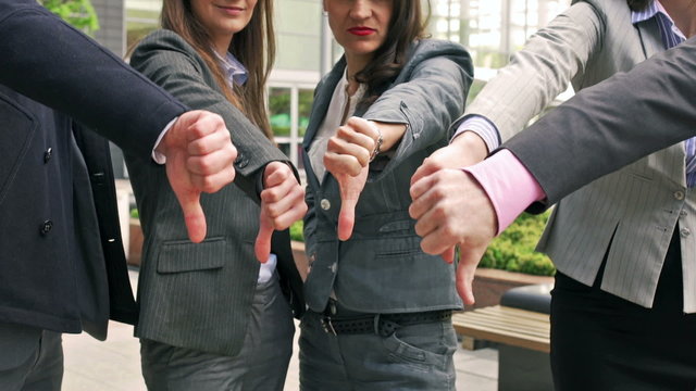 Businesspeople showing fingers down to the camera
