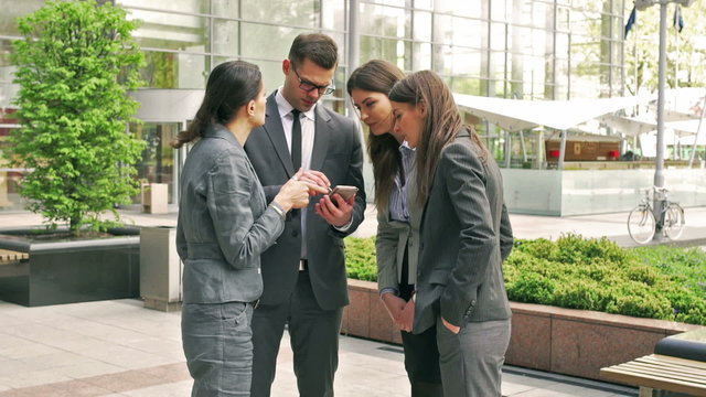 Businesspeople standing and working together on smartphone
