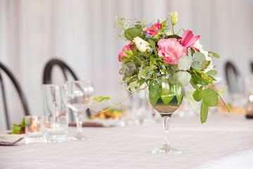 Flower arrangement of white roses and ivy is a crystal glass on the table