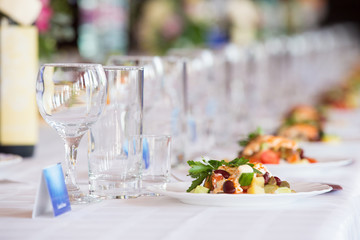 Empty glasses and plates of hors d'oeuvres are served at the table with a white tablecloth