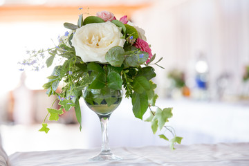 Flower arrangement of white roses and ivy is a crystal glass