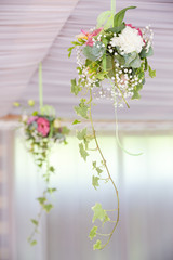 Two flower arrangements of delicate flowers hang from the ceiling
