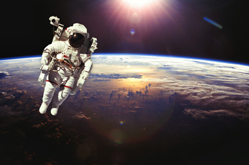 Astronaut in outer space above the earth during sunset. Elements