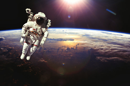 Fototapeta Astronaut in outer space above the earth during sunset. Elements