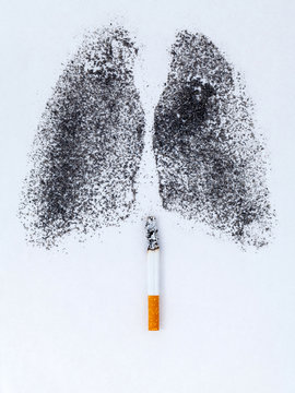 Shape of lungs with charcoal powder and cigarette on white backg