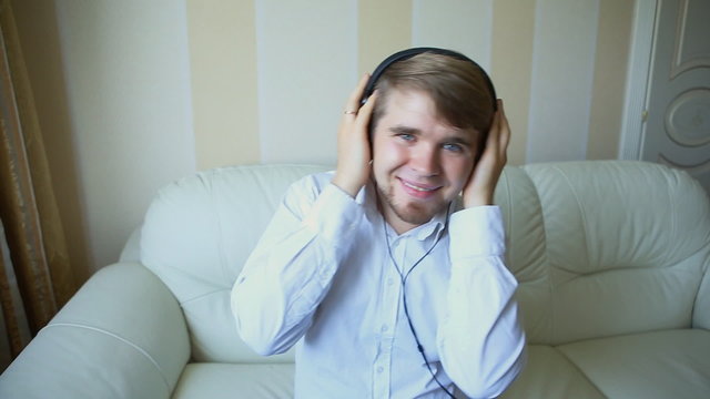 Young man relaxing with headphones, listening to music with eyes closed, smiling