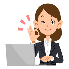OKのサインを出すビジネスウーマンとノートパソコン