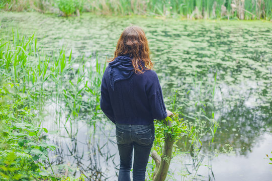 Young woman by pond in forest