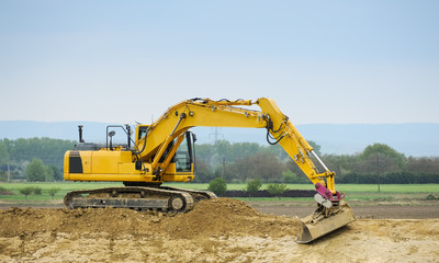 Gelber Bagger bei der Arbeit am Damm