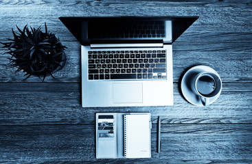 Office desk with laptop computer, planner, cup of tea