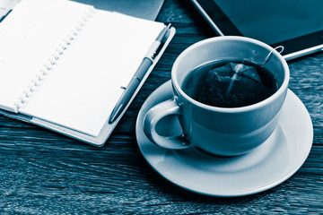 Obraz na płótnie Canvas Office desk with laptop computer, planner, cup of tea