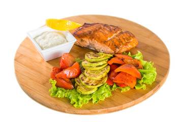 Salmon steak with grilled vegetables, sauce and lemon
