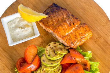 Salmon steak with grilled vegetables, sauce and lemon

