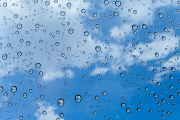 Drops of rain on glass and blue sky background / drops on glass