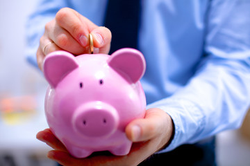 Businessman holding piggy box ,standing in office