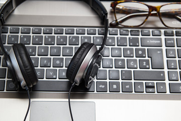 Obraz na płótnie Canvas Headphones on laptop with eyeglasses