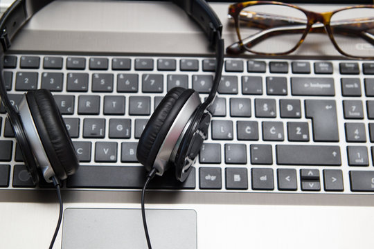 Headphones on laptop with eyeglasses