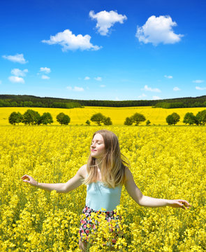 Young happy woman on blooming rapeseed field in spring