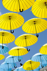 Yellow and blue umbrellas under a cloudy sky.