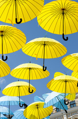Obraz na płótnie Canvas Yellow and blue umbrellas under a cloudy sky.