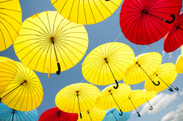Fototapeta na wymiar Yellow and blue, red umbrellas under a cloudy sky.