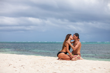 Young couple sitting together on a sand by ocean