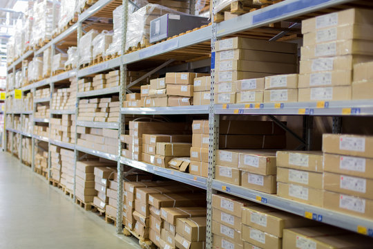 Rows of shelves with boxes and other goods in modern warehouse