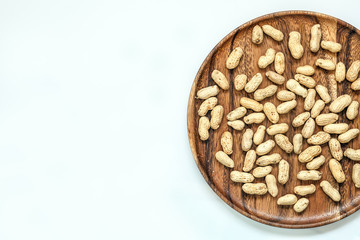 Roasted peanuts on wooden dish and white background