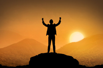 Silhouette business man standing top of the mountain