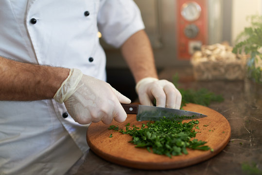 Cook chops fresh herbs on  wooden board