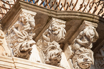 View of some typical baroque mascarons under the balconies of Cosentini Palace in Ragusa Ibla, Sicily - obrazy, fototapety, plakaty