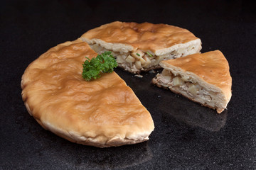 Chicken and potato pie with a segment cut out against black marble background © yarlander