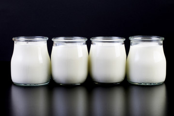 glass jars with yogurt on a black background