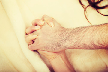 Fototapeta premium Hands of female and male lying on bed