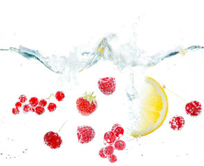 Fresh fruits and berries splashing in water isolated on white