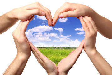 Beautiful field in heart formed by male and female hands isolated on white