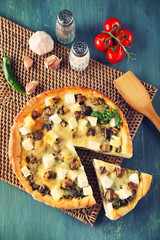 Cheese pie with mushrooms, herbs and sour creme, on wicker mat, on wooden table background