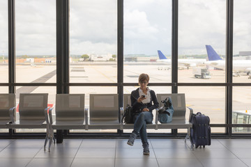 Waiting in airport terminal using phone