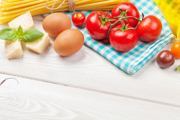 Pasta, tomatoes, basil on wooden table