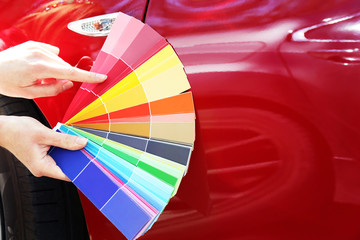 Female hands with paint samples choosing color for painting car, closeup