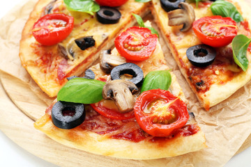Tasty pizza with vegetables and basil on cutting board close up