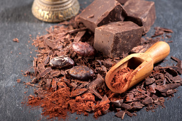 Chocolate, cocoa beans and cocoa powder on a stone background