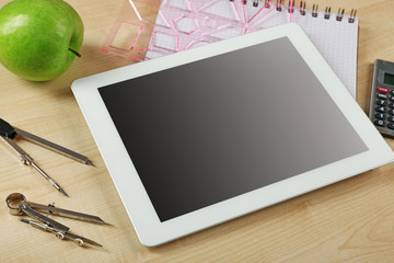 Tablet and school supplies on wooden table, closeup