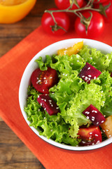 Bowl of fresh green salad on table with napkin, closeup