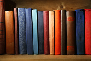 Old books on shelf, close-up, on dark wooden background
