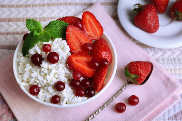 Bowl of cottage cheese with strawberry and cranberry on table, closeup